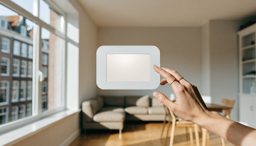 Funk-Alarmzentrale mit Touchscreen an der Wand eines hellen Wohnzimmers, eine Hand bedient das Panel