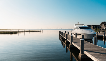 Weiße Motoryacht an einem Holzsteg in einem niederländischen Yachthafen