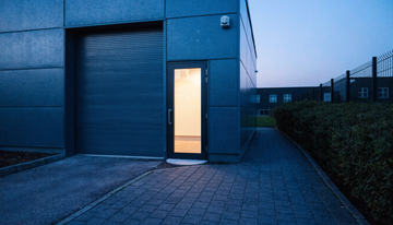 Gewerbeeinheit mit Rolltor und Außensirene an der Fassade am Abend